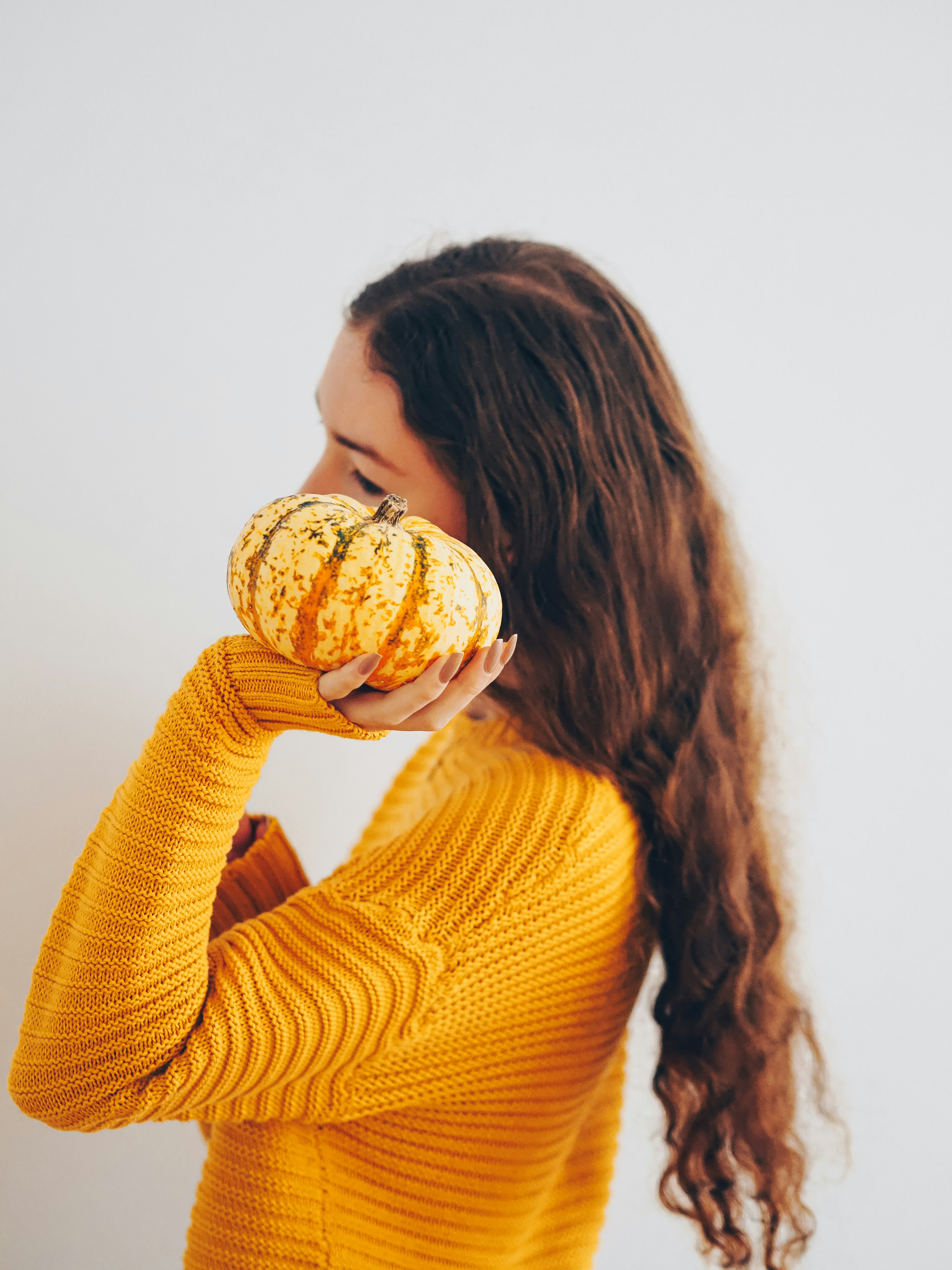 woman in yellow sweater holding white and brown pastry